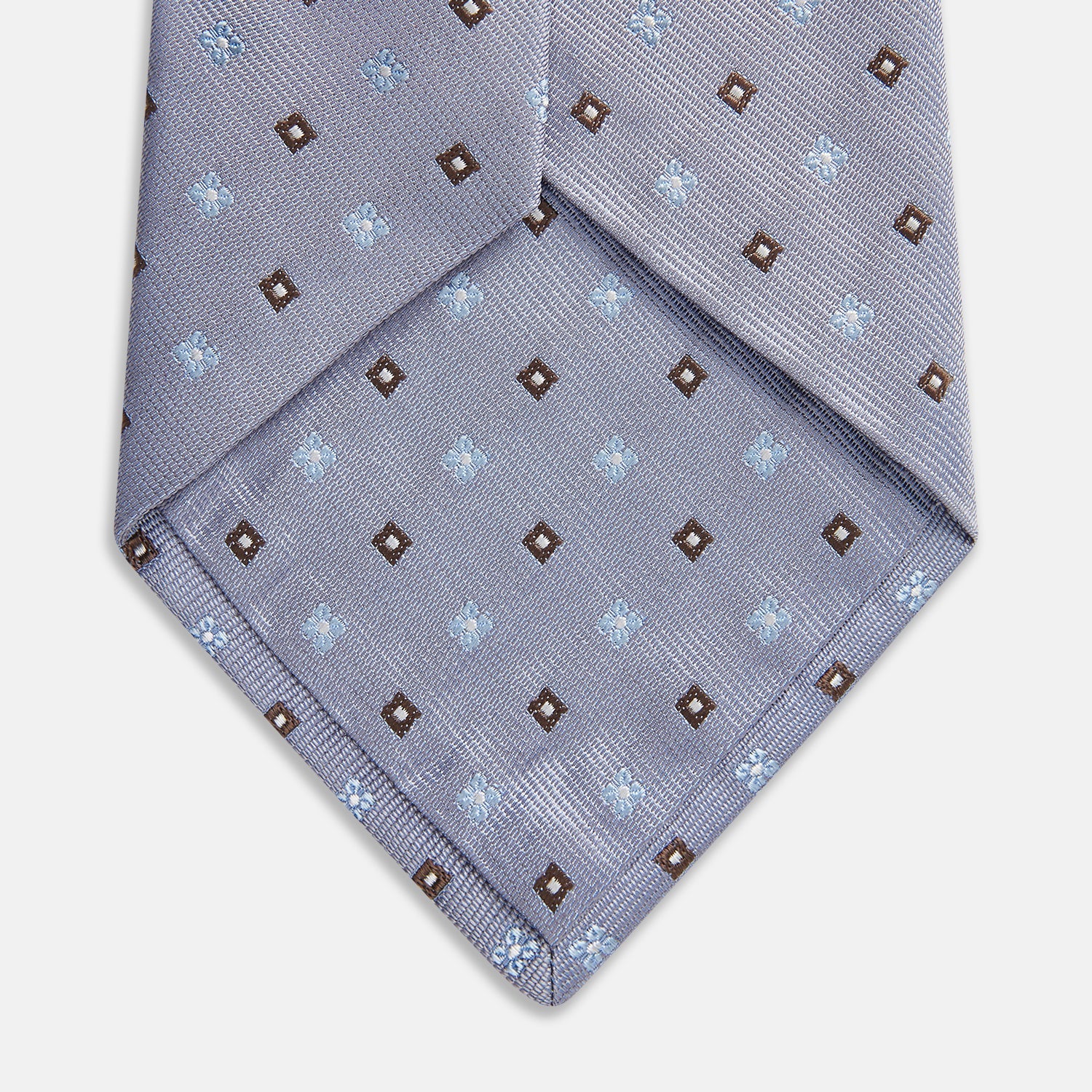 View 3 of product The Pale Blue Multi Floret Silk Tie by Turnbull & Asser features light purple silk with a pale blue floret pattern and small brown squares—perfect for pairing with a classic Turnbull & Asser shirt.