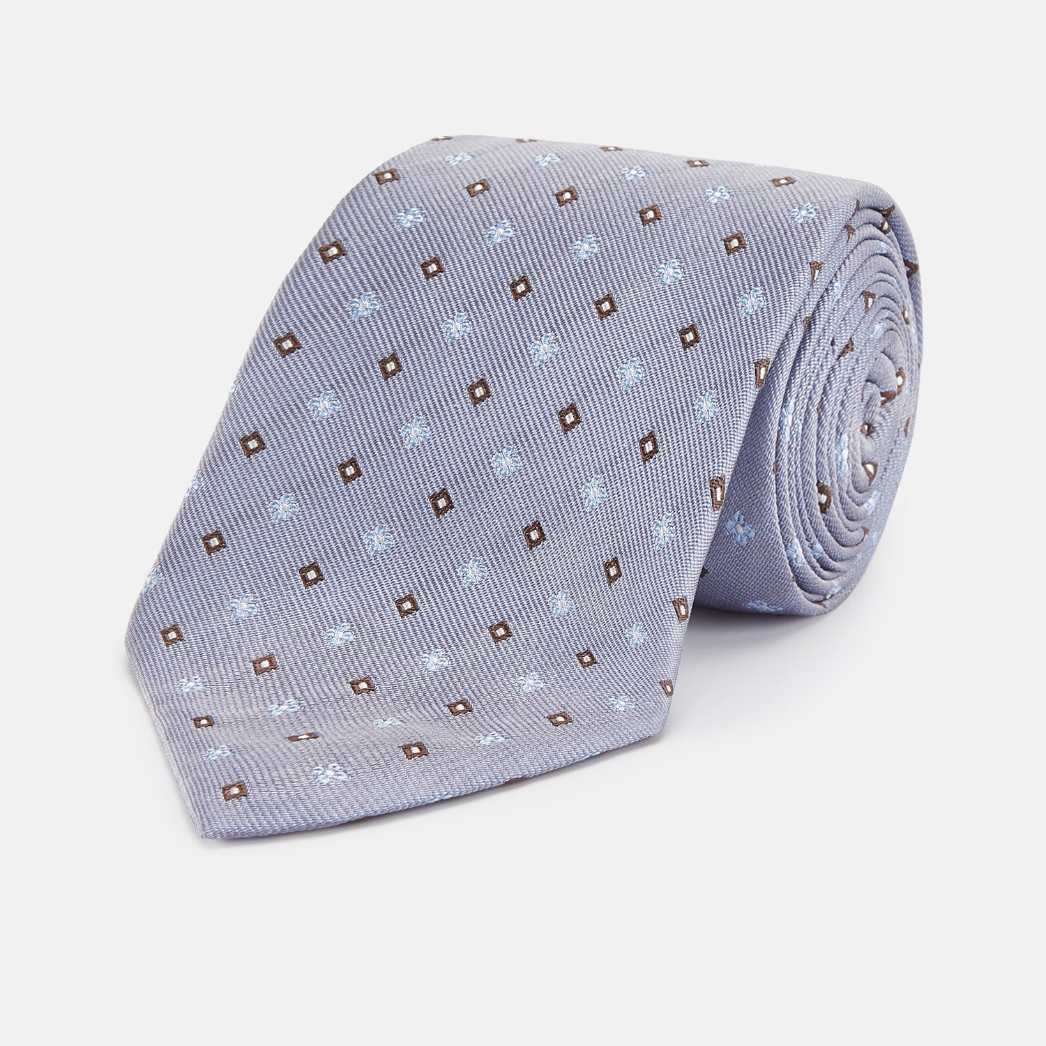 View 1 of product The Pale Blue Multi Floret Silk Tie by Turnbull & Asser features light purple silk with a pale blue floret pattern and small brown squares—perfect for pairing with a classic Turnbull & Asser shirt.