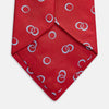 View 3 of product The Turnbull & Asser Red Geometric Rings Silk Tie, made in England, features a rolled-up design with small overlapping light blue circles on red silk and is displayed against a plain white background.