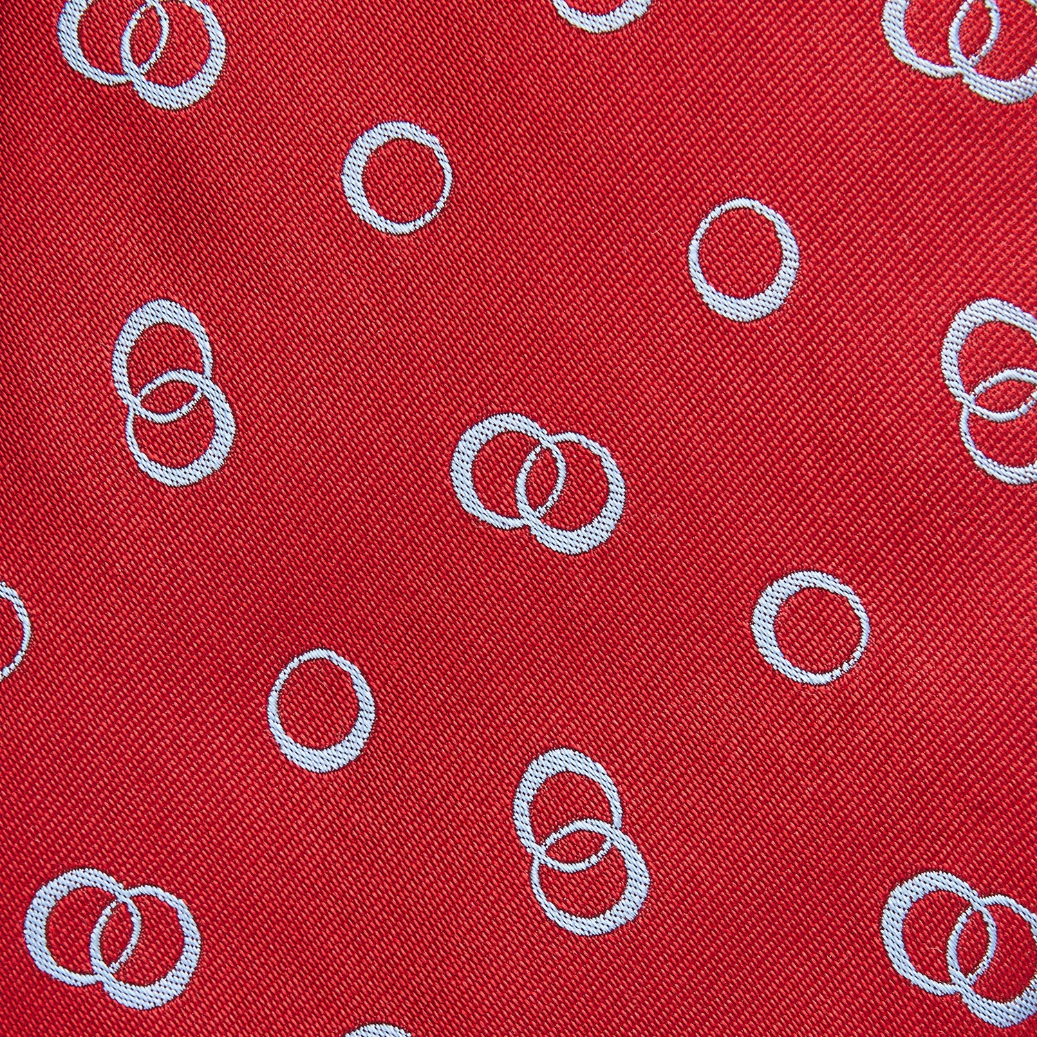 View 2 of product The Turnbull & Asser Red Geometric Rings Silk Tie, made in England, features a rolled-up design with small overlapping light blue circles on red silk and is displayed against a plain white background.
