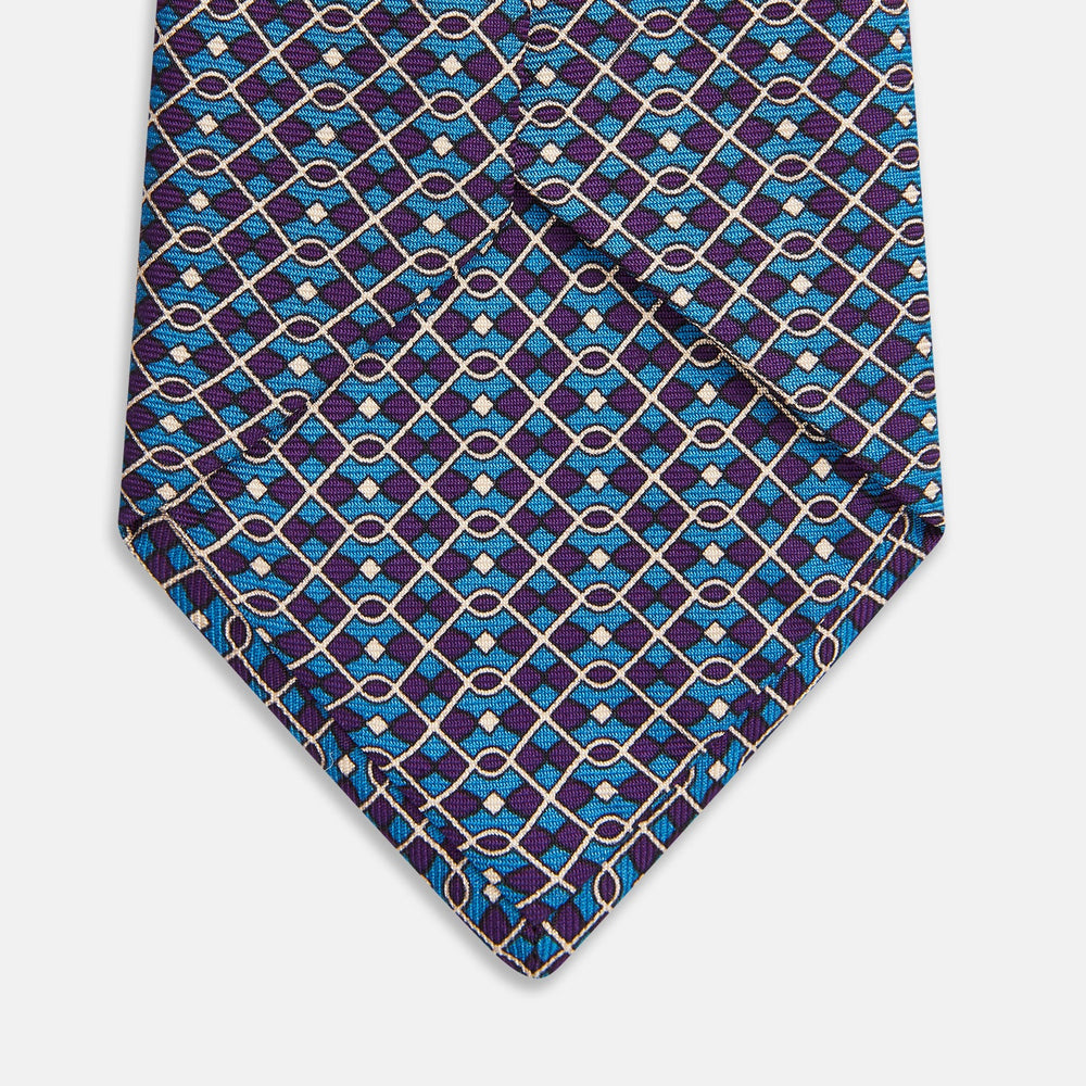 A rolled-up Pale Blue and Purple Art Deco Silk Tie by Turnbull & Asser, handmade in England, is displayed on a plain white background.