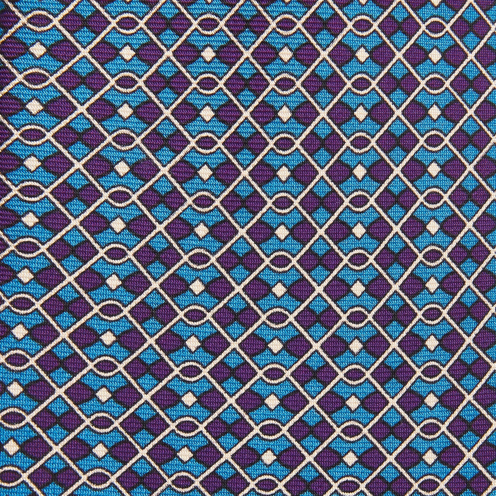 A rolled-up Pale Blue and Purple Art Deco Silk Tie by Turnbull & Asser, handmade in England, is displayed on a plain white background.