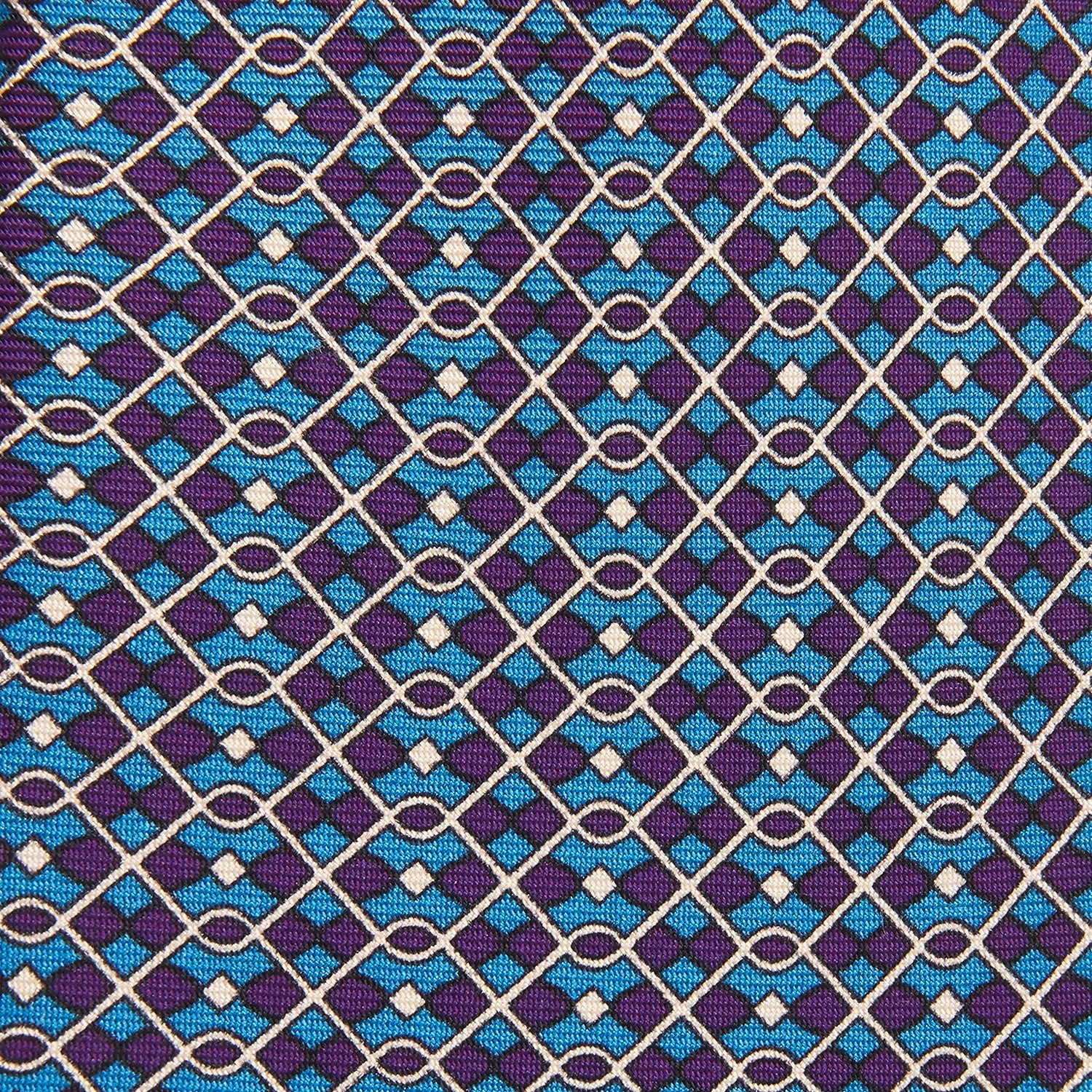 View 2 of product A rolled-up Pale Blue and Purple Art Deco Silk Tie by Turnbull & Asser, handmade in England, is displayed on a plain white background.