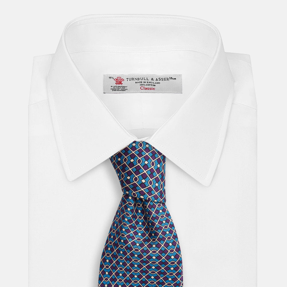 A rolled-up Pale Blue and Purple Art Deco Silk Tie by Turnbull & Asser, handmade in England, is displayed on a plain white background.