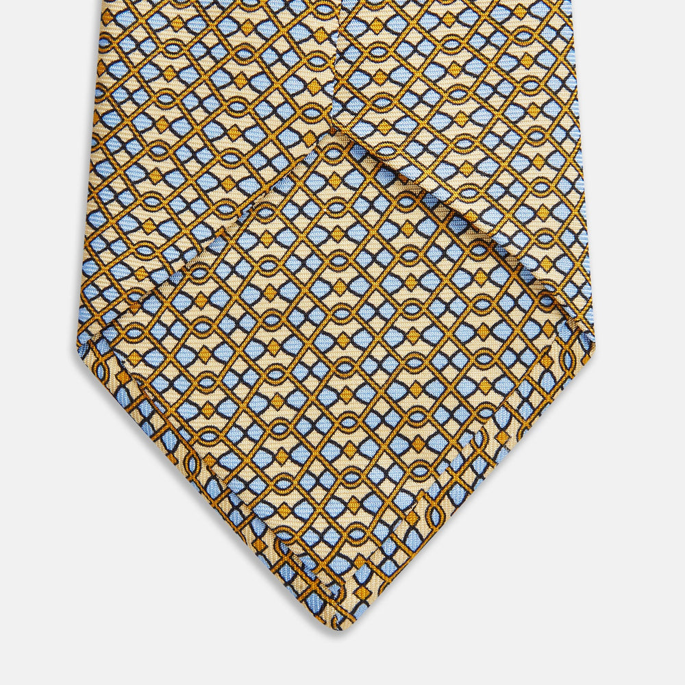 The Turnbull & Asser Yellow and Pale Blue Art Deco Silk Tie features interlocking yellow, blue, and black geometric shapes on white, adding a bold touch to any ensemble.