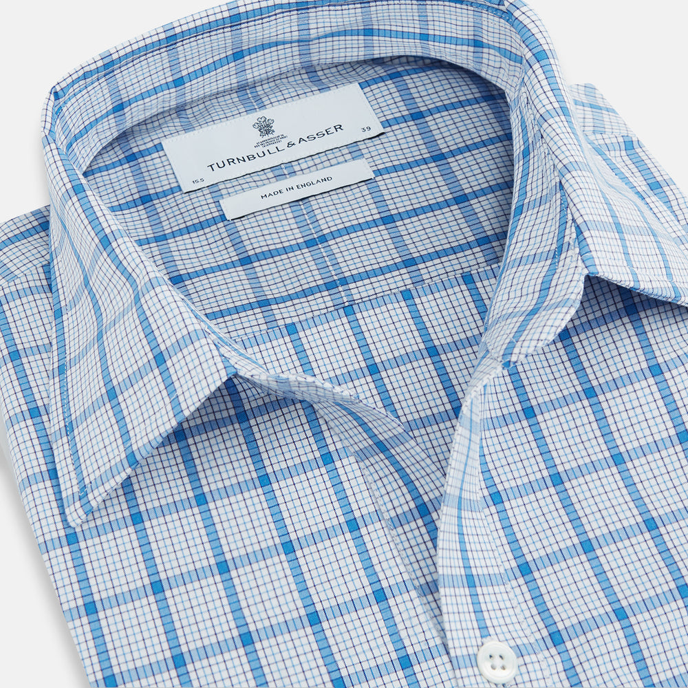 The Turnbull & Asser Blue Graph Overlay Check Piccadilly Shirt is a breathable cotton button-up featuring a collar, two chest pockets, white buttons, and an elegant blue graph check—perfect for the holidays.