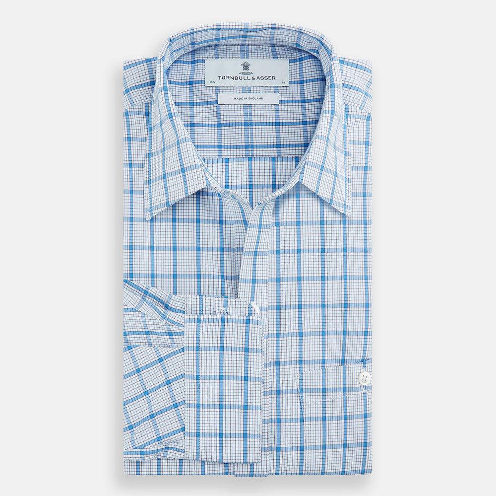 The Turnbull & Asser Blue Graph Overlay Check Piccadilly Shirt is a breathable cotton button-up featuring a collar, two chest pockets, white buttons, and an elegant blue graph check—perfect for the holidays.