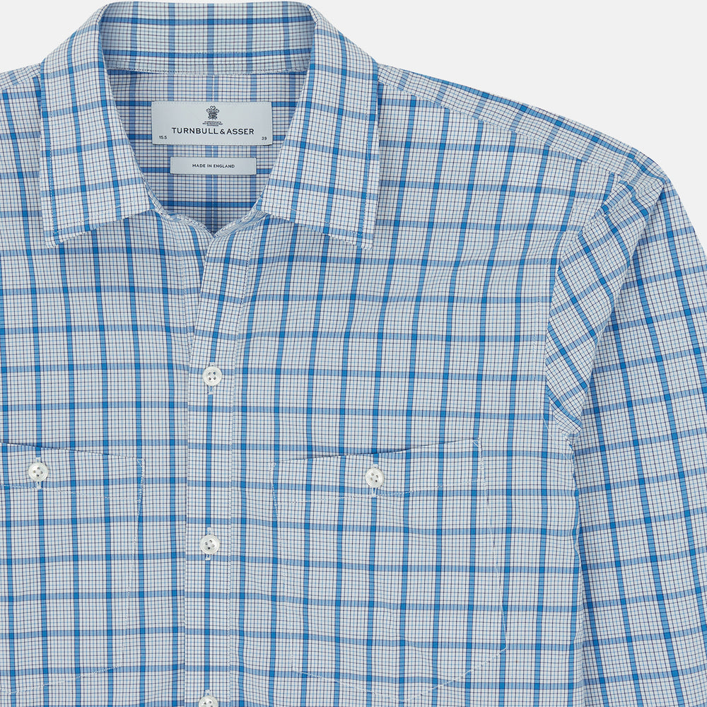 The Turnbull & Asser Blue Graph Overlay Check Piccadilly Shirt is a breathable cotton button-up featuring a collar, two chest pockets, white buttons, and an elegant blue graph check—perfect for the holidays.