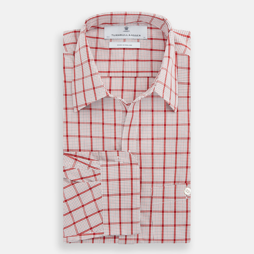 The Turnbull & Asser Red Graph Overlay Check Piccadilly Shirt is a cotton, long-sleeve button-up with a white base, red graph check pattern, collar, two chest flap pockets, and white buttons on the front and cuffs.