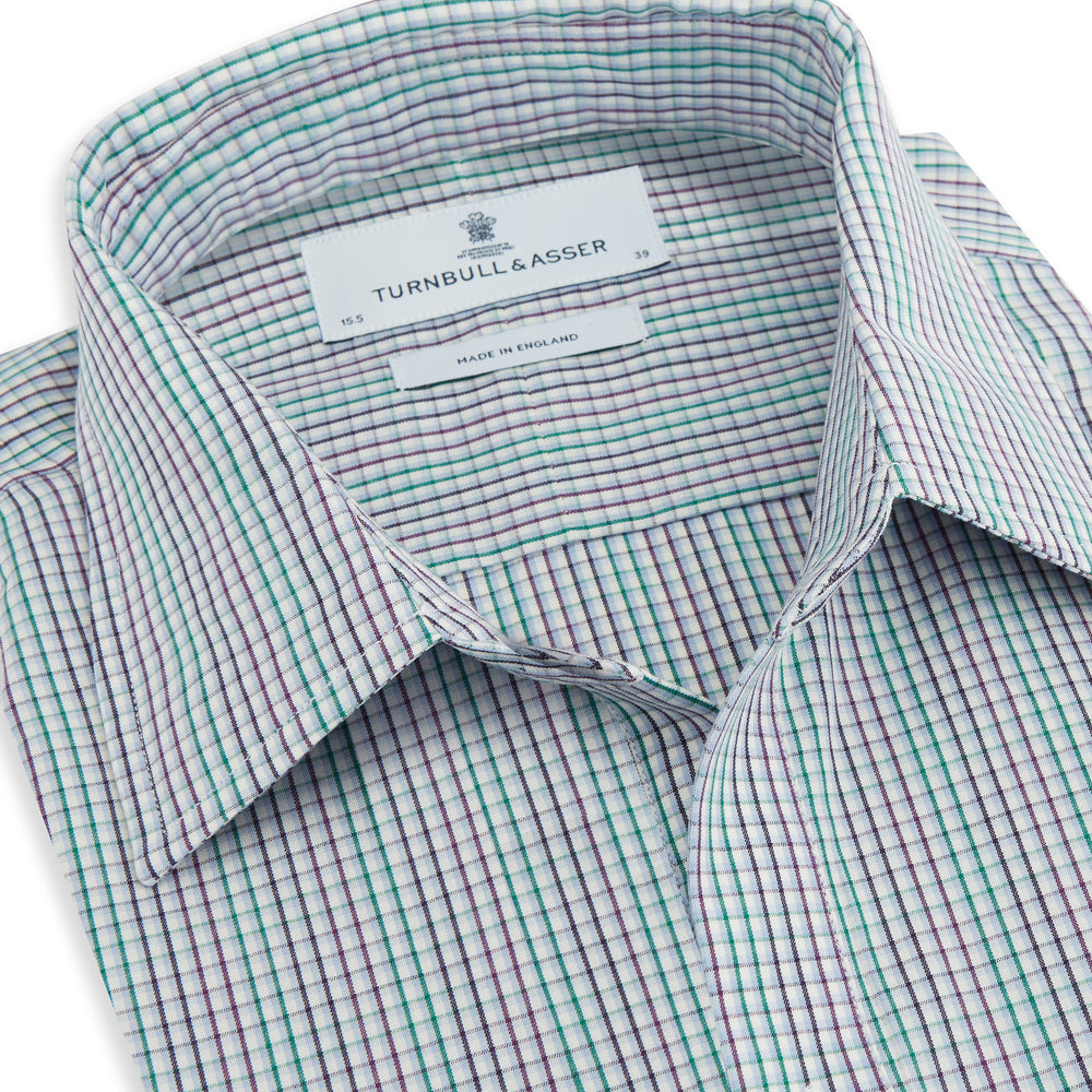 The Turnbull & Asser Green Graph Overlay Micro Check Piccadilly Shirt is a breathable cotton, long-sleeve button-up featuring a green micro check in light blue and white, two chest pockets with buttoned flaps, and white buttons.