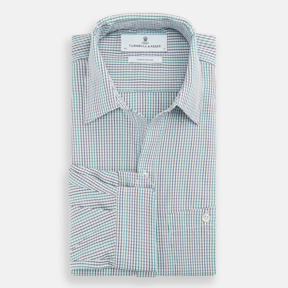 The Turnbull & Asser Green Graph Overlay Micro Check Piccadilly Shirt is a breathable cotton, long-sleeve button-up featuring a green micro check in light blue and white, two chest pockets with buttoned flaps, and white buttons.
