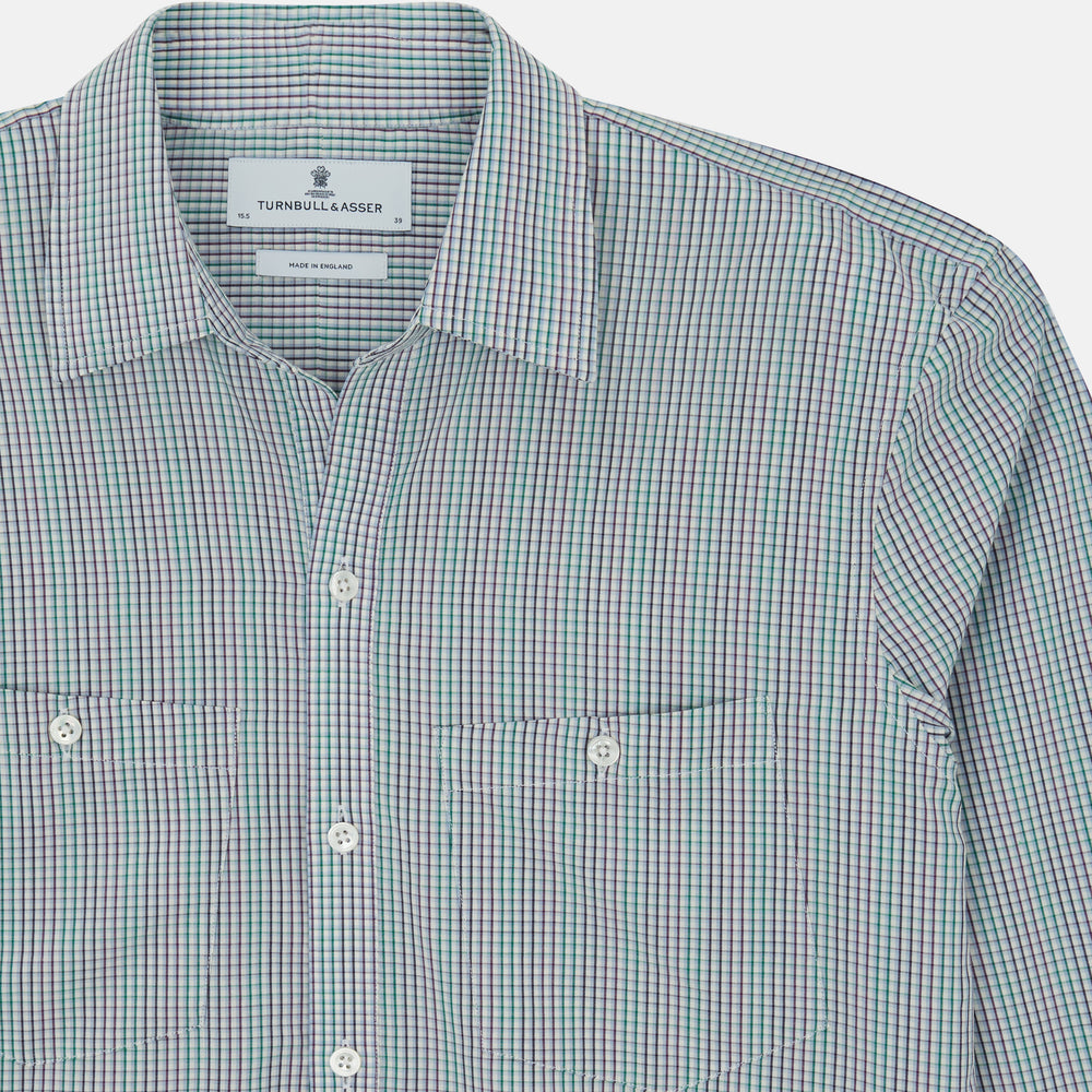 The Turnbull & Asser Green Graph Overlay Micro Check Piccadilly Shirt is a breathable cotton, long-sleeve button-up featuring a green micro check in light blue and white, two chest pockets with buttoned flaps, and white buttons.