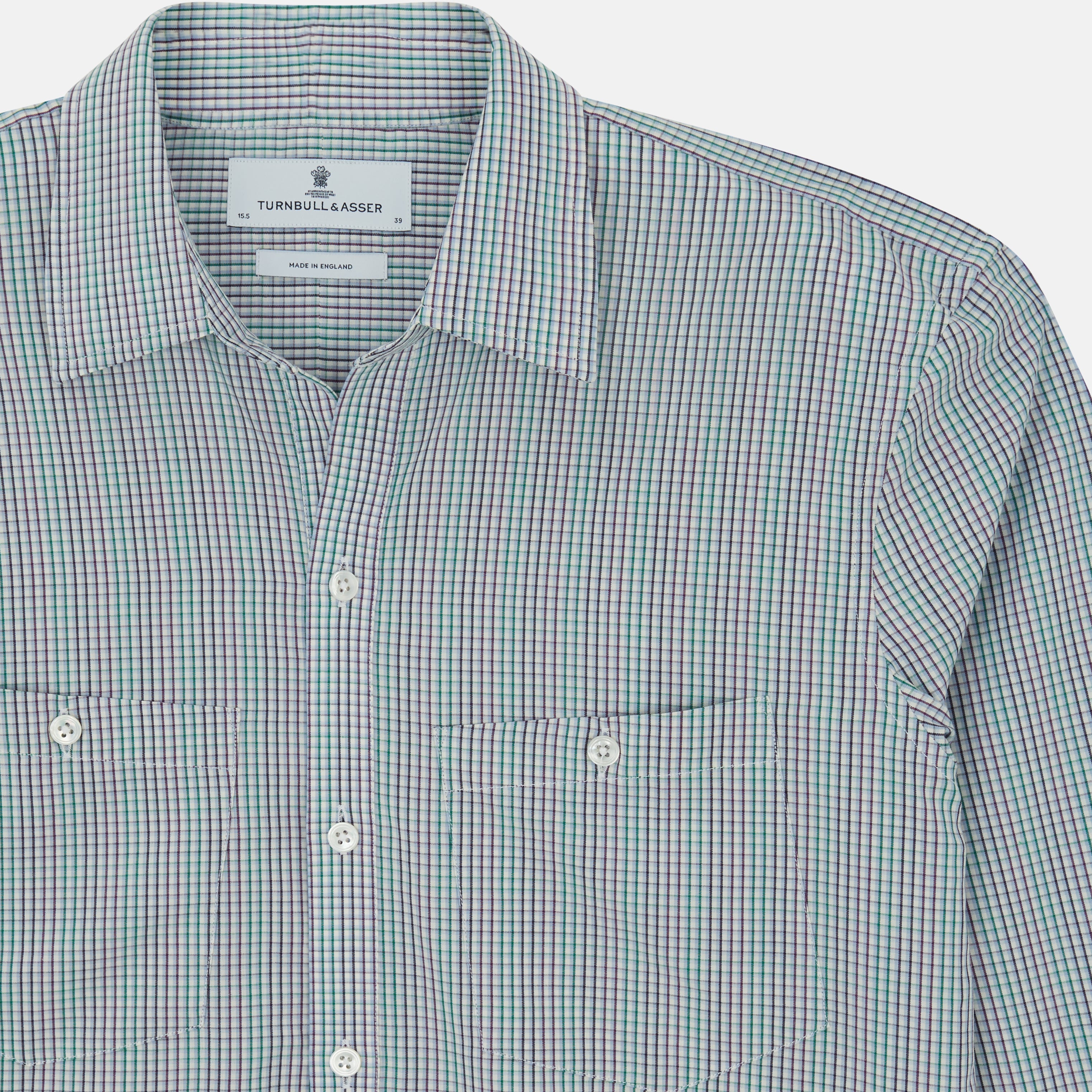 View 4 of product The Turnbull & Asser Green Graph Overlay Micro Check Piccadilly Shirt is a breathable cotton, long-sleeve button-up featuring a green micro check in light blue and white, two chest pockets with buttoned flaps, and white buttons.