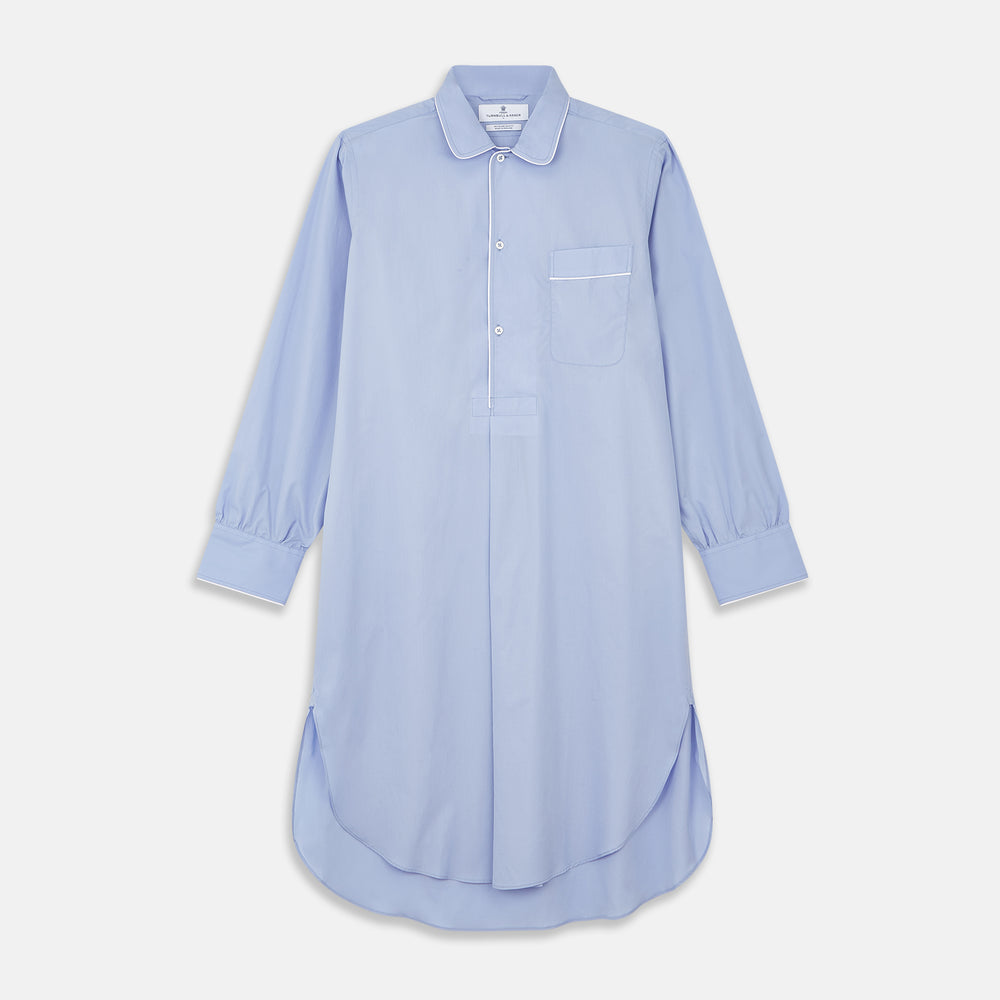 The Turnbull & Asser Blue Piped Sea Island Quality Cotton Nightshirt features light blue sea island cotton, a collared neckline with white piping, a front pocket, partial button placket, and a curved high-low hem for classic nightshirt style.