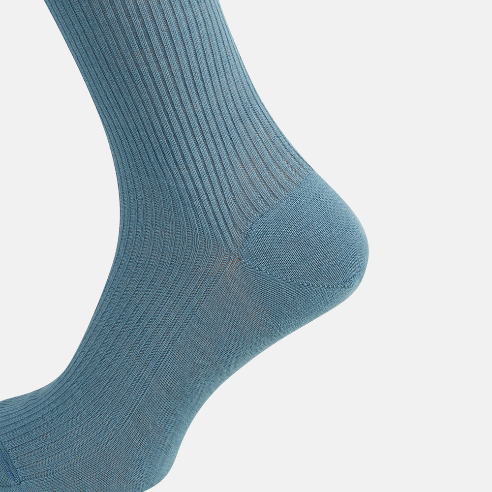 A single Pale Blue Mid-Length Merino Sock by Turnbull & Asser stands upright against a white background, highlighting its ribbed texture and reinforced toe and heel—showcasing the elegance of luxury merino wool.