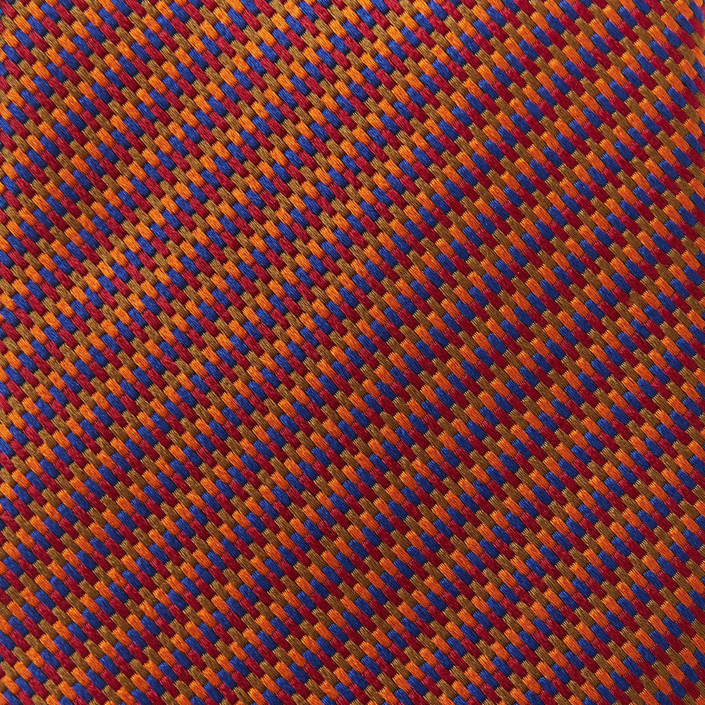 The Turnbull & Asser Die Another Day Stripe Silk Tie, as seen on James Bond, showcases a vibrant orange, red, and purple woven pattern, elegantly rolled and displayed against a white background.