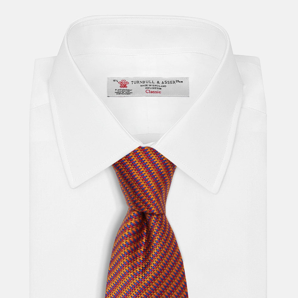 The Turnbull & Asser Die Another Day Stripe Silk Tie, as seen on James Bond, showcases a vibrant orange, red, and purple woven pattern, elegantly rolled and displayed against a white background.