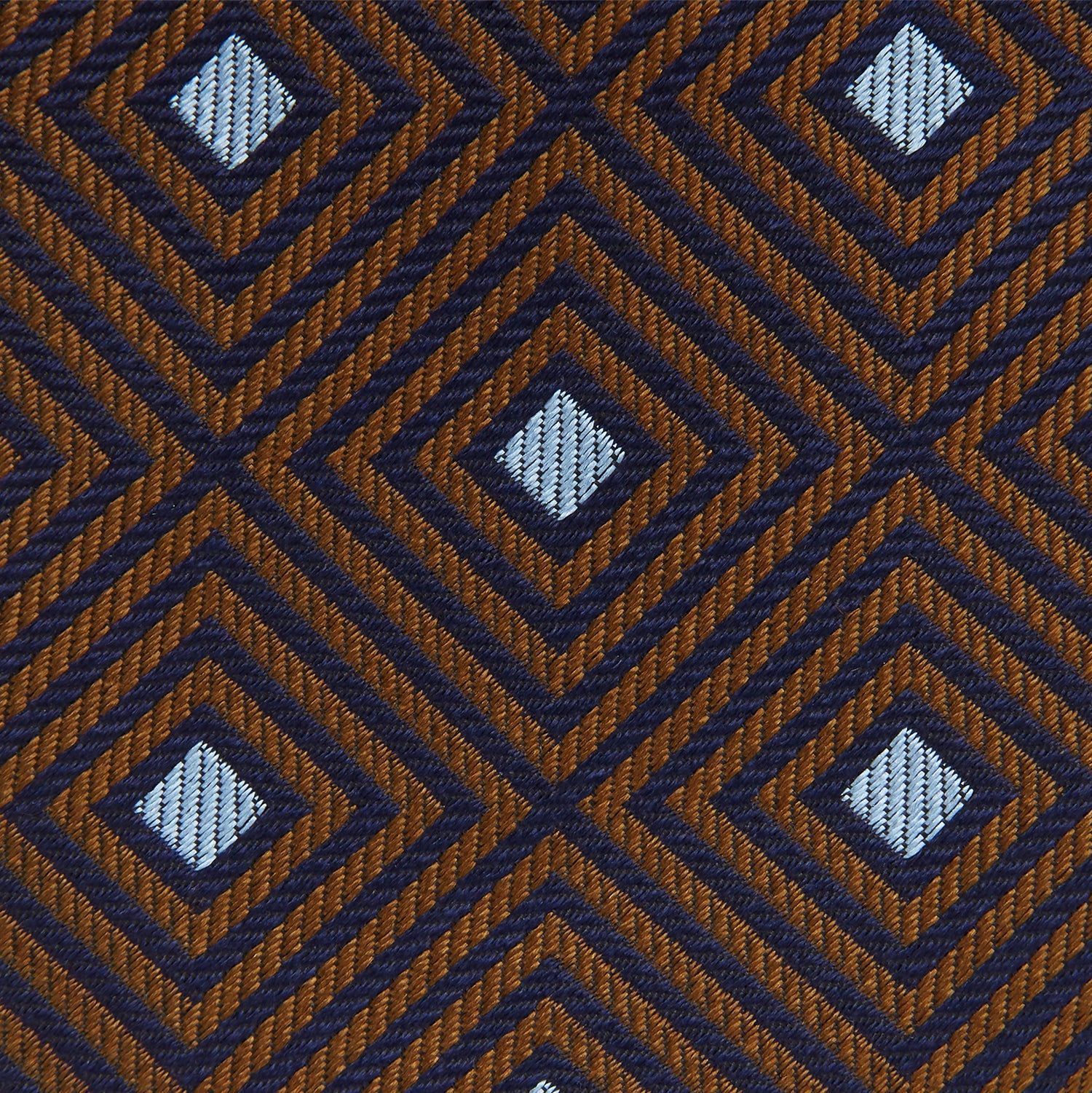 View 4 of product The Tomorrow Never Dies Square Silk Tie by Turnbull & Asser, as seen on James Bond, features a brown and blue geometric diamond pattern on a dark background—an ideal accessory for any Bond-inspired look. Displayed rolled on a plain white surface.