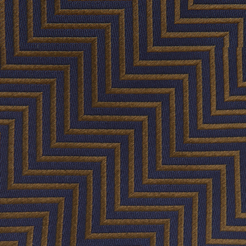 Turnbull & Asser's "The World Is Not Enough" Zig Zag Silk Tie, as seen on James Bond, features a bold navy blue and gold chevron design and is shown neatly rolled on a white background.