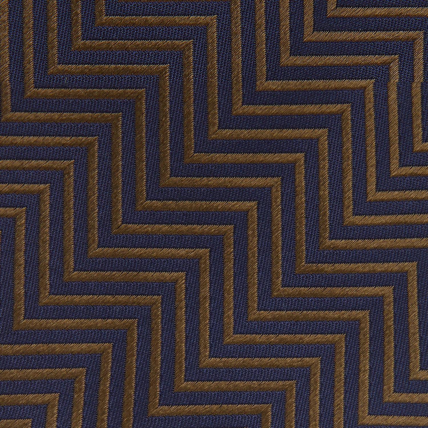 View 4 of product Turnbull & Asser's "The World Is Not Enough" Zig Zag Silk Tie, as seen on James Bond, features a bold navy blue and gold chevron design and is shown neatly rolled on a white background.
