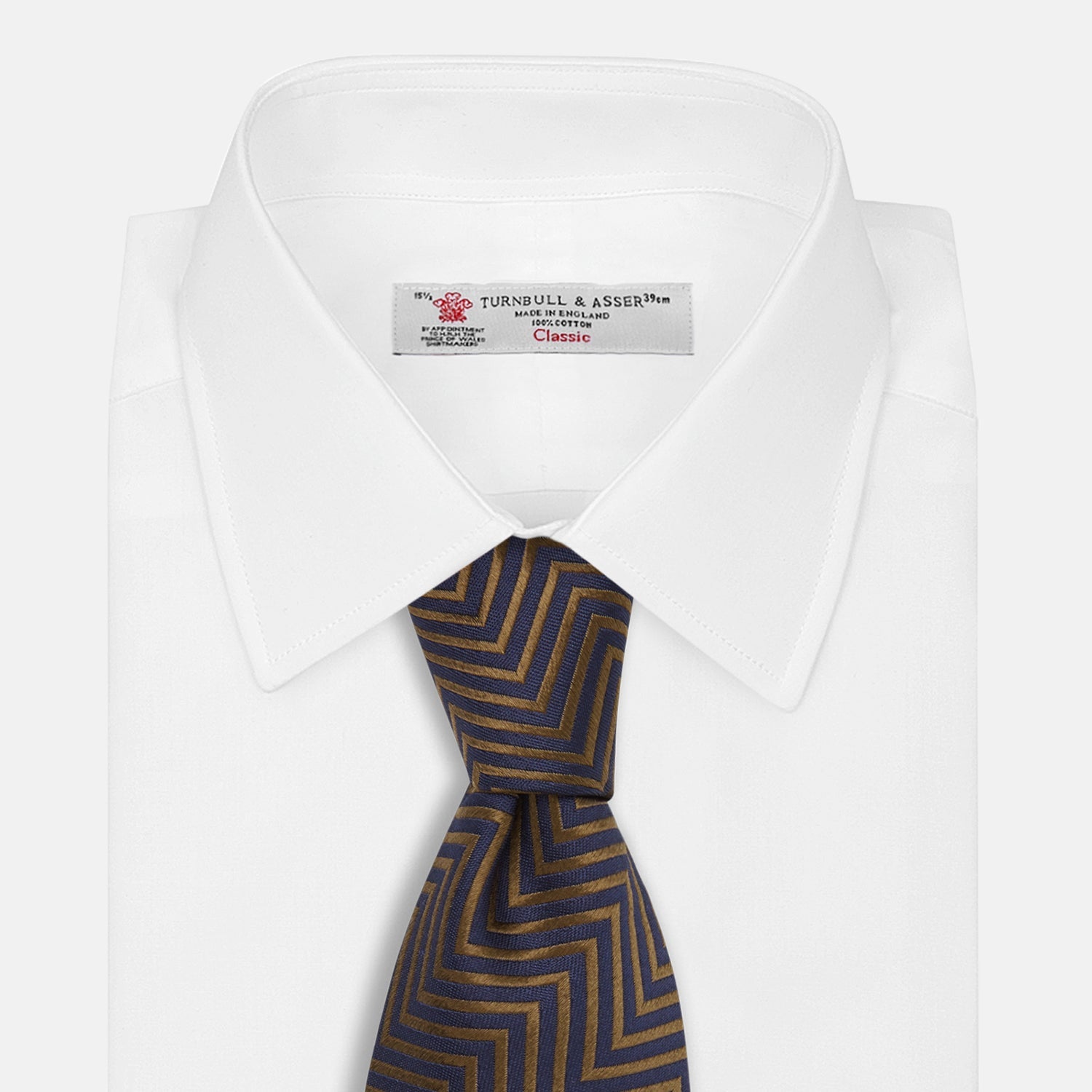 View 3 of product Turnbull & Asser's "The World Is Not Enough" Zig Zag Silk Tie, as seen on James Bond, features a bold navy blue and gold chevron design and is shown neatly rolled on a white background.