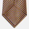 View 5 of product The Turnbull & Asser Tomorrow Never Dies Diamond Silk Tie, as seen on James Bond, features a gold and navy checkered pattern—an ideal gift for any Bond fan. Displayed rolled against a plain white background.
