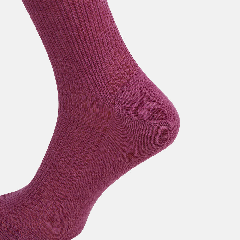 A single Turnbull & Asser Mauve Mid-Length Merino Sock is shown upright, foot angled downward, against a plain light gray background. The ribbed sock features a solid mauve color.