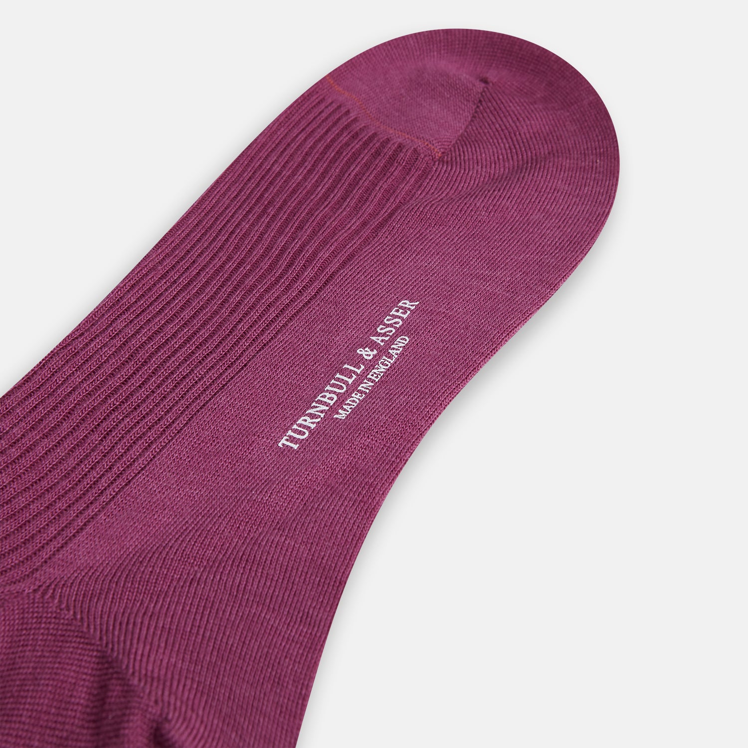 View 3 of product A single Turnbull & Asser Mauve Mid-Length Merino Sock is shown upright, foot angled downward, against a plain light gray background. The ribbed sock features a solid mauve color.