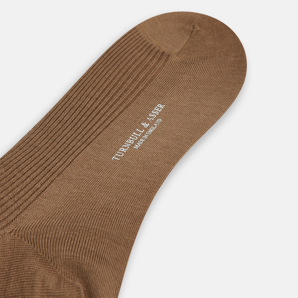 A single Turnbull & Asser Camel Mid-Length Merino Sock stands upright on a plain white background, showcasing its ribbed texture and reinforced toe and heel.