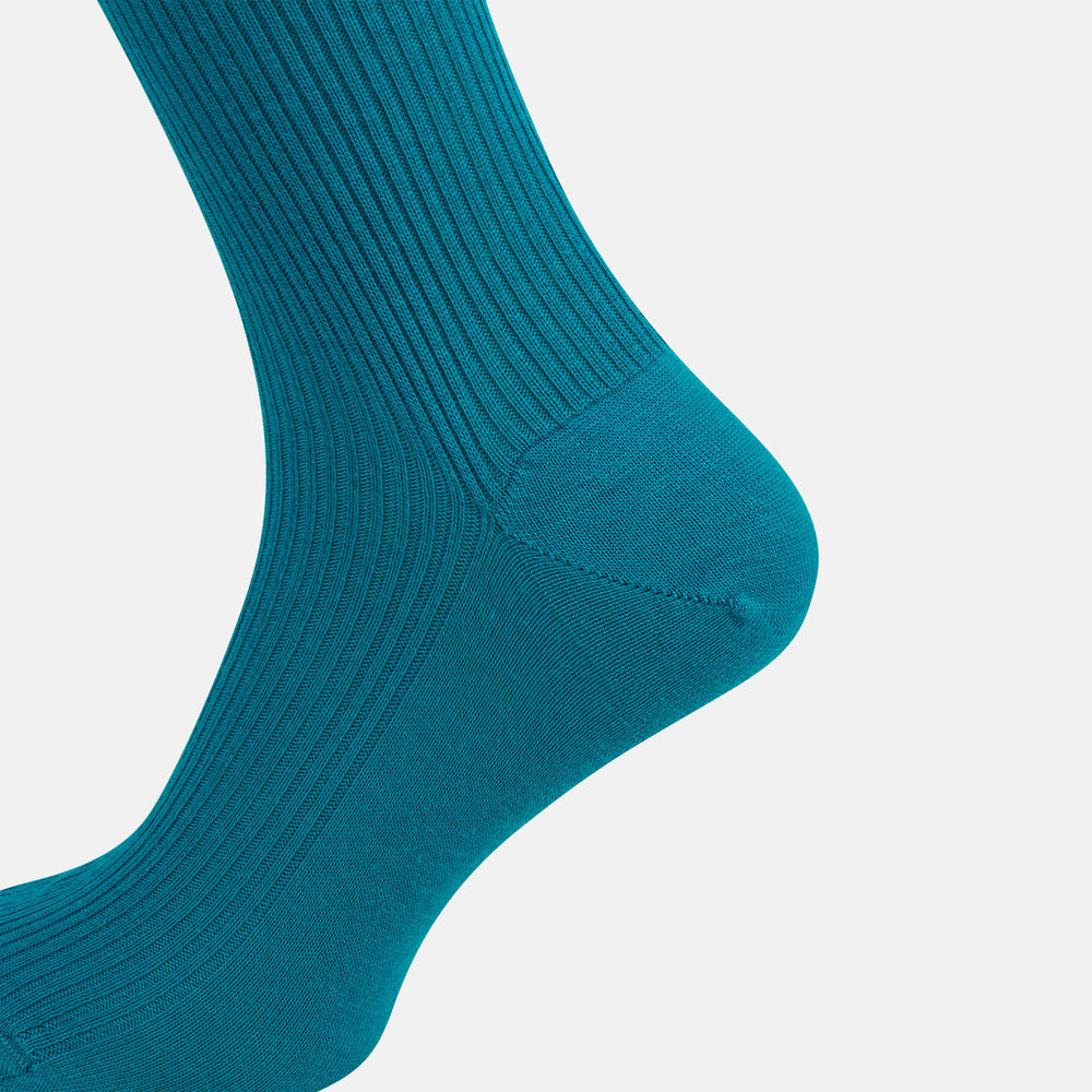 A Turnbull & Asser Turquoise Mid-Length Merino Sock stands upright on a plain light gray background, showcasing its ribbed texture and seamless toe.
