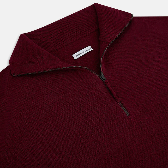 A close-up of a maroon quarter-zip sweater with a ribbed collar and a visible zipper. The inside label reads Purcell & Carder. The fabric appears soft and finely knit.