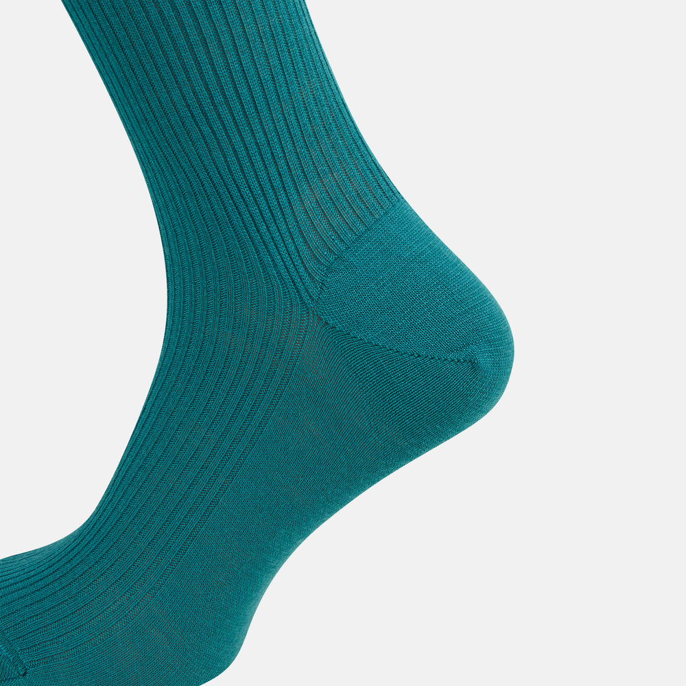 A single Turnbull & Asser Teal Mid-Length Merino Sock stands upright against a white background, featuring a ribbed texture and the signature elegance of luxury merino wool.