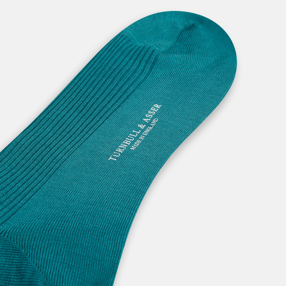 A single Turnbull & Asser Teal Mid-Length Merino Sock stands upright against a white background, featuring a ribbed texture and the signature elegance of luxury merino wool.
