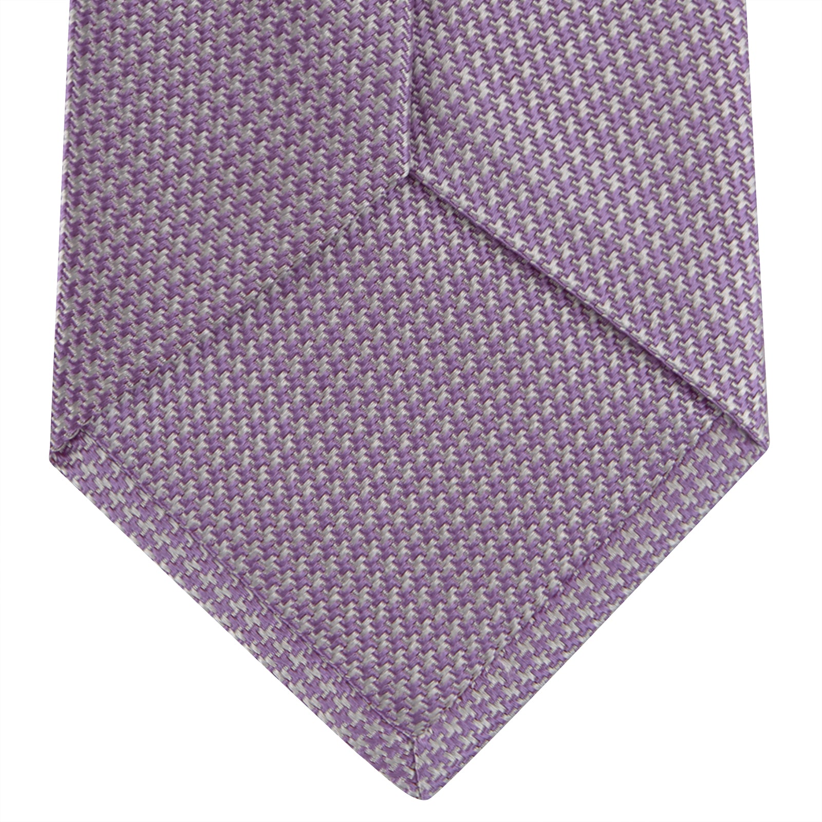 View 4 of product The Turnbull & Asser Lilac Houndstooth Silk Tie features a subtle houndstooth pattern and elegant silk weave—ideal for elevating your favorite office shirt. Displayed rolled on a white background.