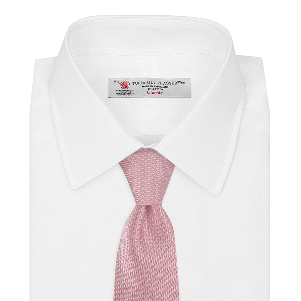 The Turnbull & Asser Pink Houndstooth Silk Tie, featuring a subtle textured pattern, is rolled up and displayed on a plain white background—ideal for pairing with your favorite office shirt.