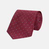 View 1 of product The Turnbull & Asser Dark Pink and Blue Spot Lace Silk Tie features small, evenly spaced blue dots on dark pink silk, shown rolled up against a white background.