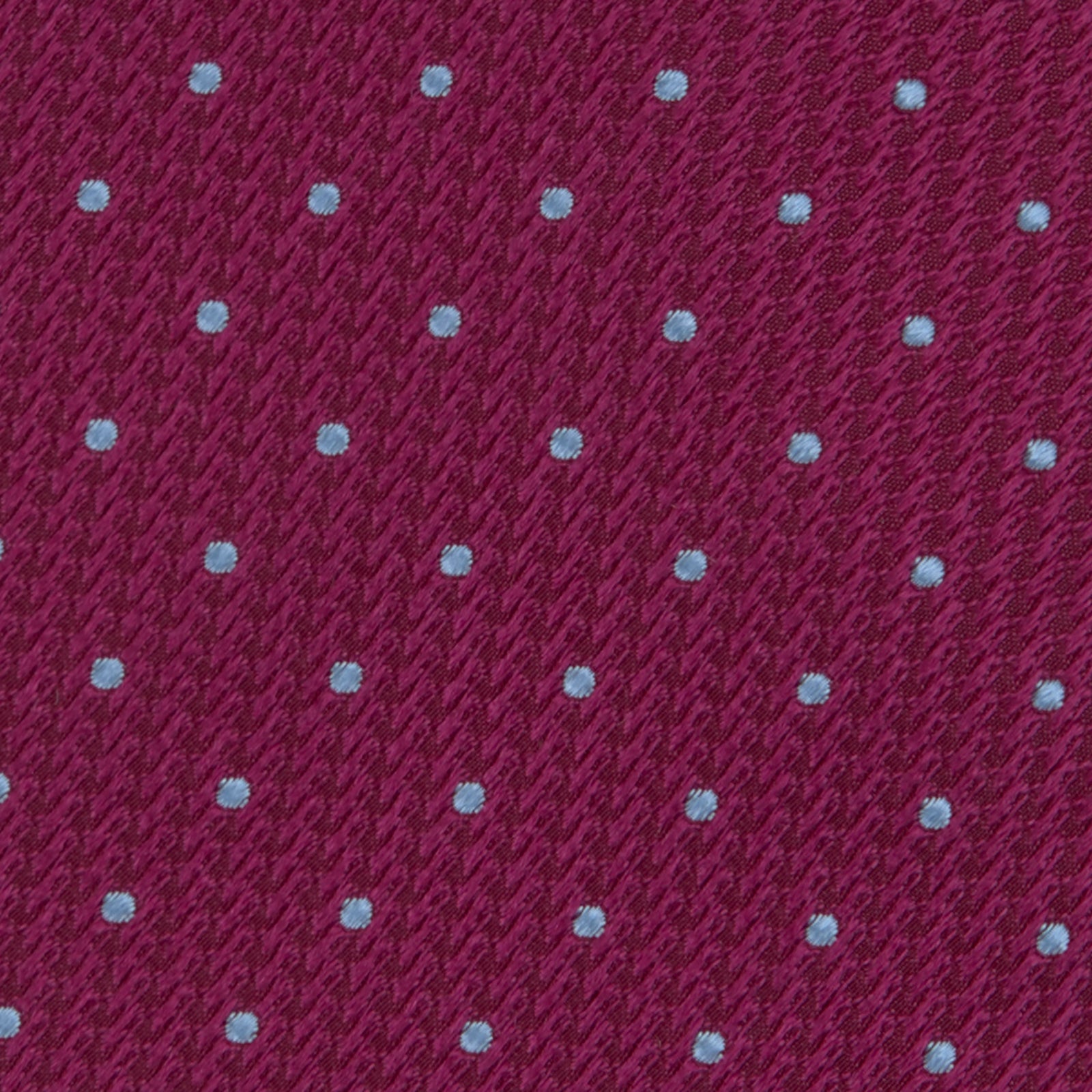 View 3 of product The Turnbull & Asser Dark Pink and Blue Spot Lace Silk Tie features small, evenly spaced blue dots on dark pink silk, shown rolled up against a white background.