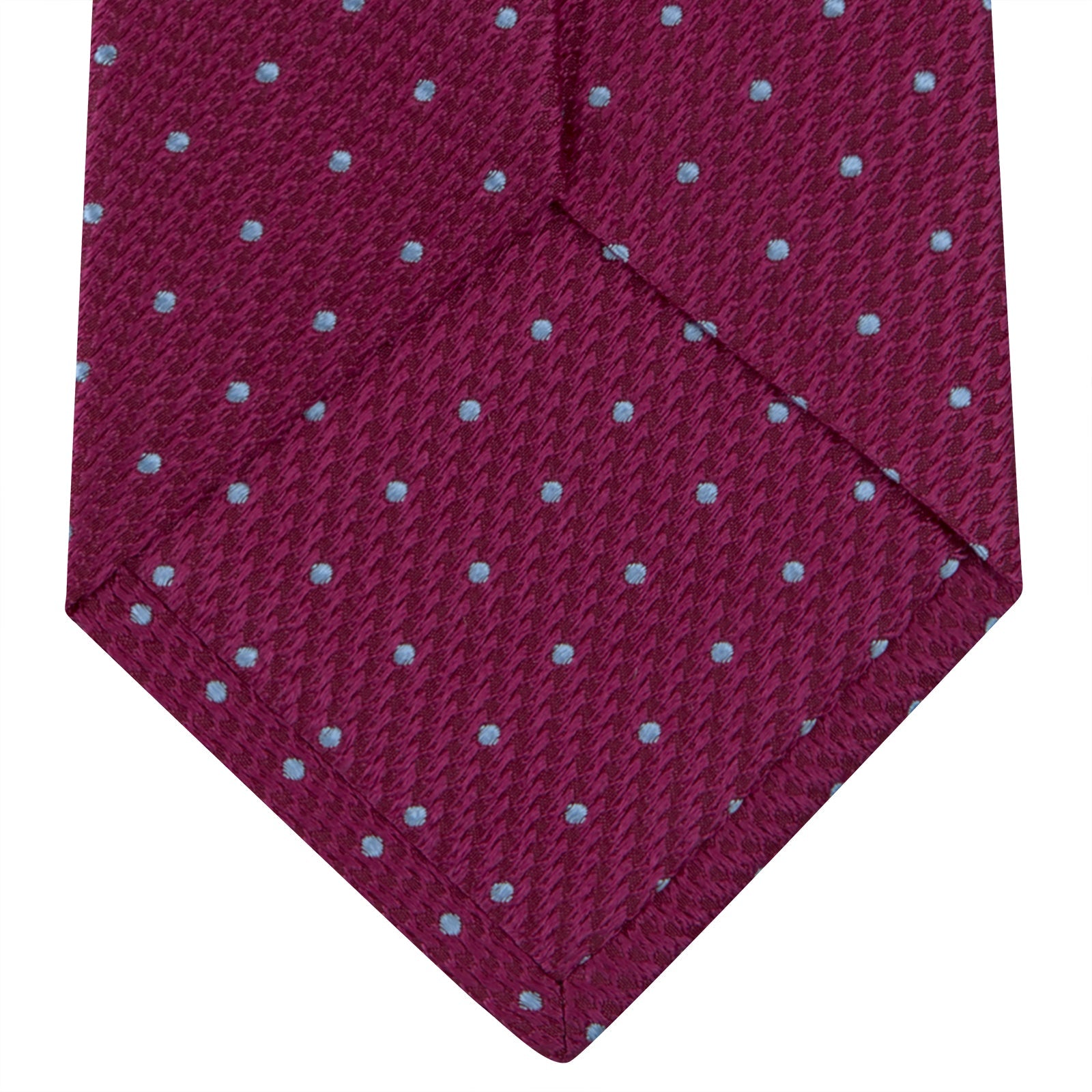 View 4 of product The Turnbull & Asser Dark Pink and Blue Spot Lace Silk Tie features small, evenly spaced blue dots on dark pink silk, shown rolled up against a white background.