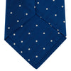 View 4 of product The Turnbull & Asser Royal Blue and White Small Spot Herringbone Silk Tie is displayed rolled at one end on a plain white background, showcasing its classic English silk design with subtle white polka dots.