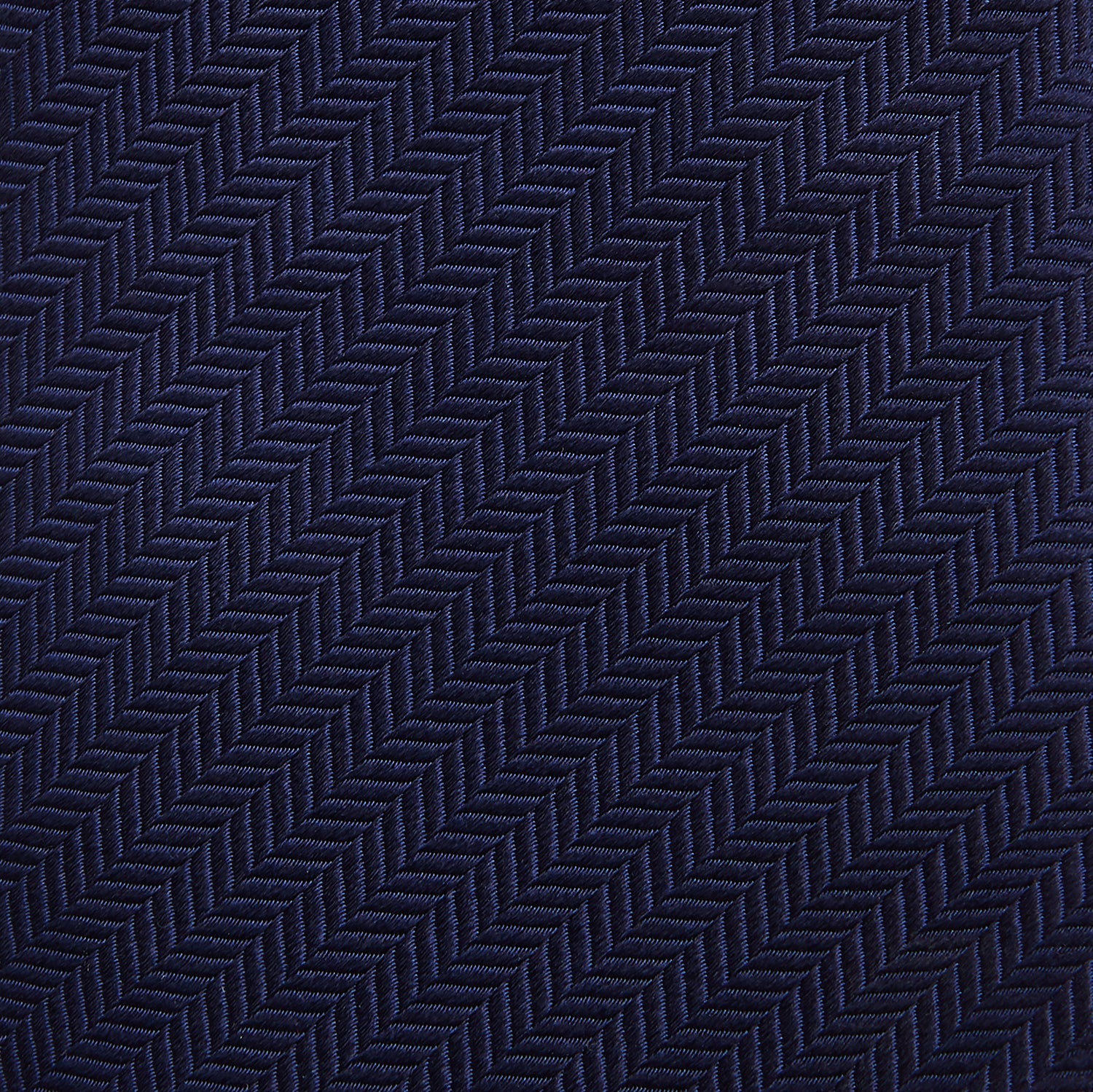 View 3 of product The Turnbull & Asser Slim Navy Herringbone Silk Tie is a refined men’s accessory, elegantly rolled and displayed on a plain white background.