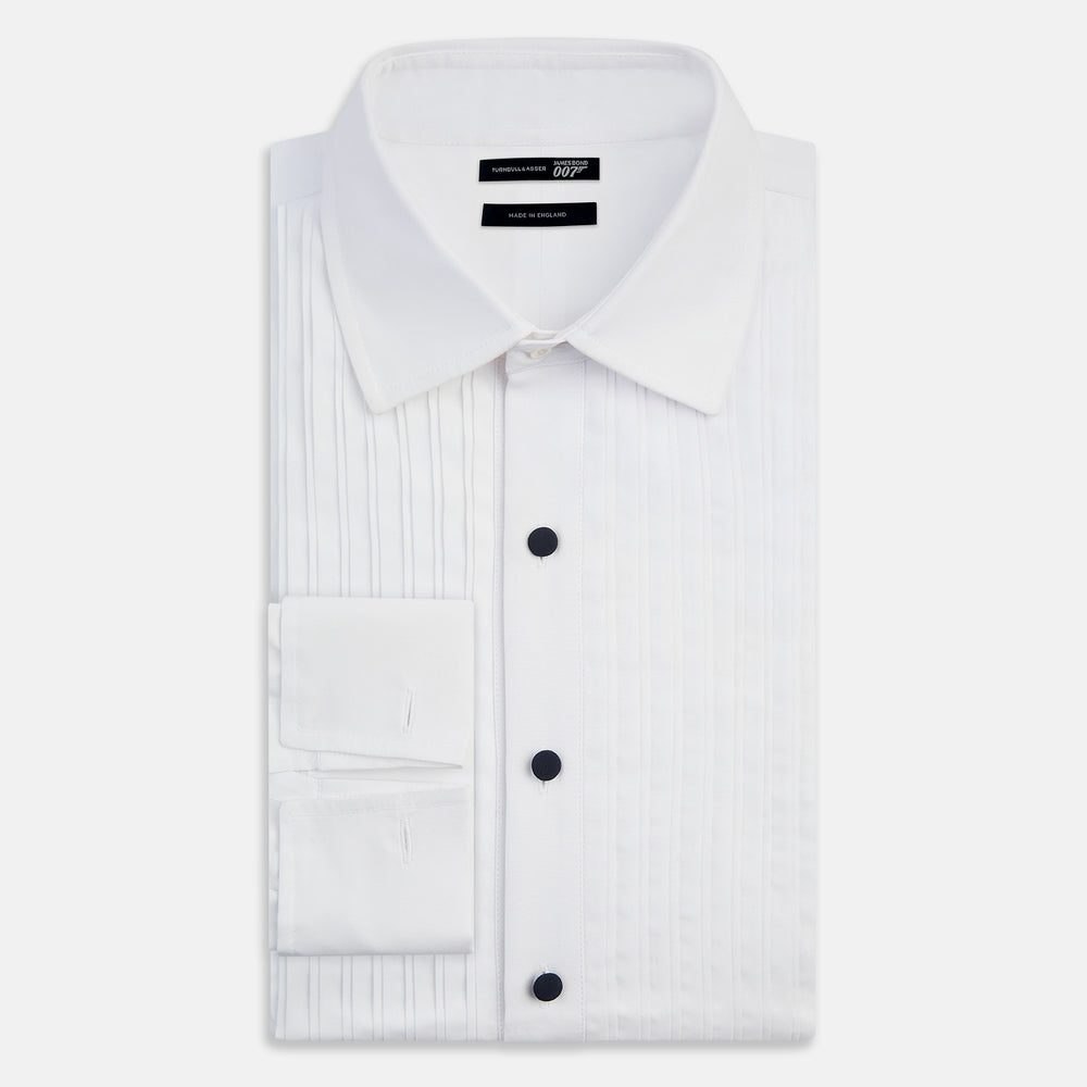 The Casino Royale White Dress Shirt in Cotton by Turnbull & Asser UK is a long-sleeve white dress shirt, crafted from crisp white cotton poplin with a pleated bib front, black buttons, and a classic collar, shown laid flat on a white background.