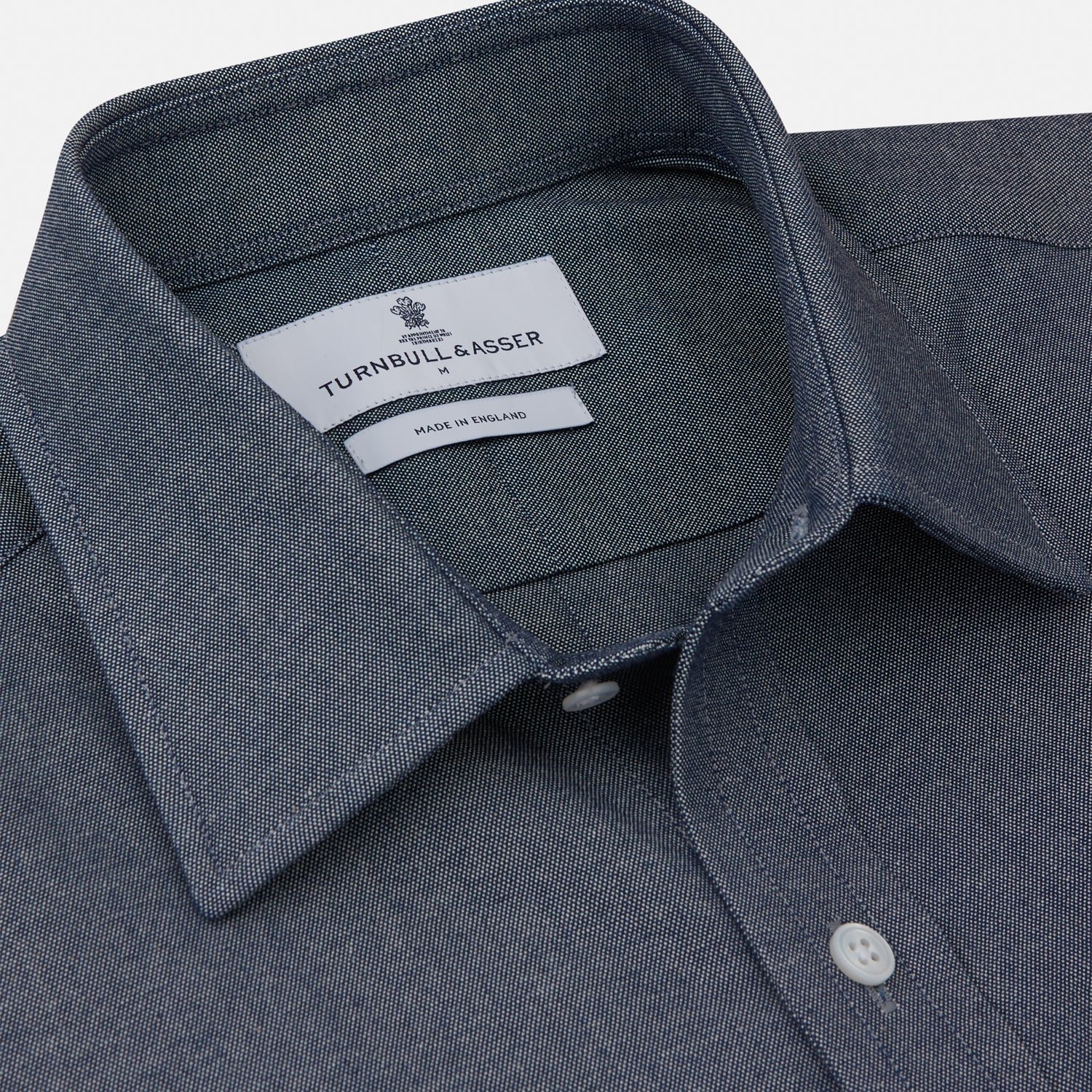 View 2 of product The Turnbull & Asser Plain Blue Oxford Weekend Fit Shirt features a Derby collar, 1-button cuffs, and a smart-casual look—perfect for weekends. Displayed flat on a white background.