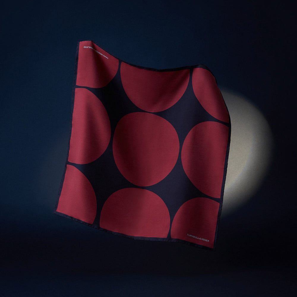 The DR. NO Red and Black Multi Spots Silk Pocket Square by Turnbull & Asser is handmade in England, featuring large red circles on black, with "Turnbull & Asser" and "Made in England" printed in white in the corners.