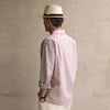 View 3 of product An older man in a light hat, Turnbull & Asser Beige Stripe Cotton Holiday Fit Shirt with Revere Collar & Single Button Cuff, and white pants leans casually against a tall concrete pillar outdoors, greenery blurred behind him.