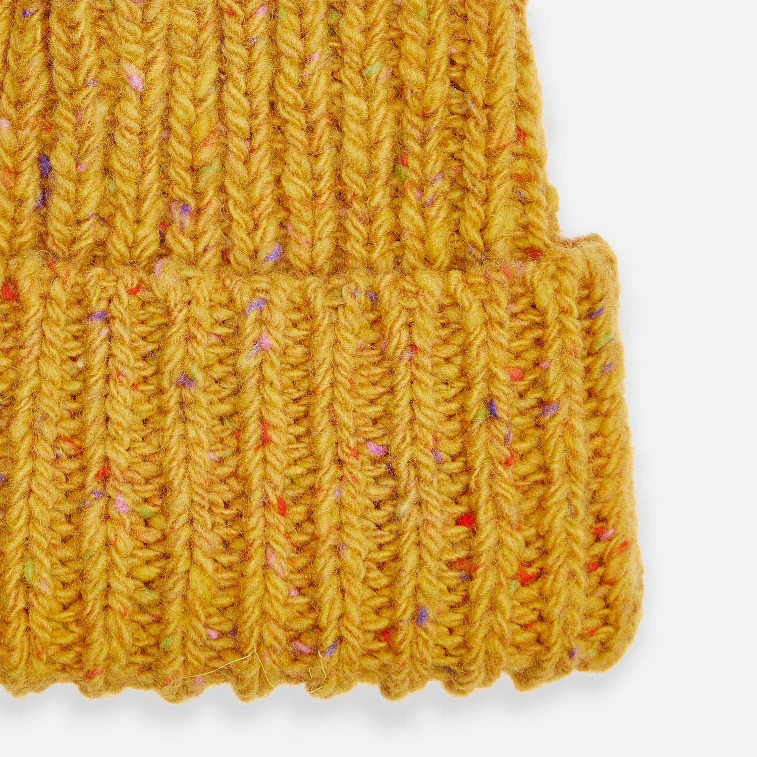 View 2 of product The Turnbull & Asser Yellow Donegal Ribbed Merino Hat features a mustard hue, folded brim, and subtle multicolored flecks in the yarn. Shown on a white background.
