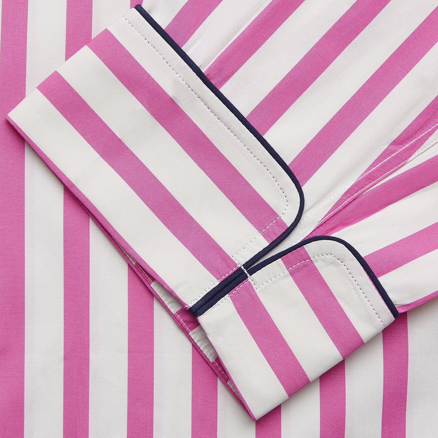 View 5 of product The Turnbull & Asser Pink Candy Stripe Cotton Traditional Pyjamas feature long sleeves, pants, vertical pink candy stripes, a camp collar shirt with buttons, chest pocket, and navy trim on the pocket and cuffs.