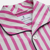 View 4 of product The Turnbull & Asser Pink Candy Stripe Cotton Traditional Pyjamas feature long sleeves, pants, vertical pink candy stripes, a camp collar shirt with buttons, chest pocket, and navy trim on the pocket and cuffs.