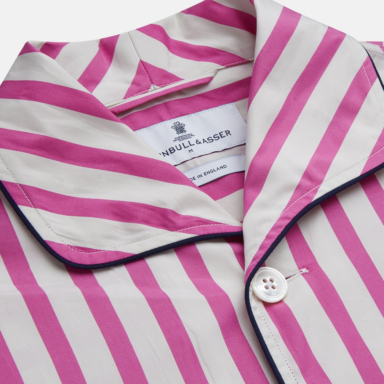 View 4 of product The Turnbull & Asser Pink Candy Stripe Cotton Traditional Pyjamas feature long sleeves, pants, vertical pink candy stripes, a camp collar shirt with buttons, chest pocket, and navy trim on the pocket and cuffs.