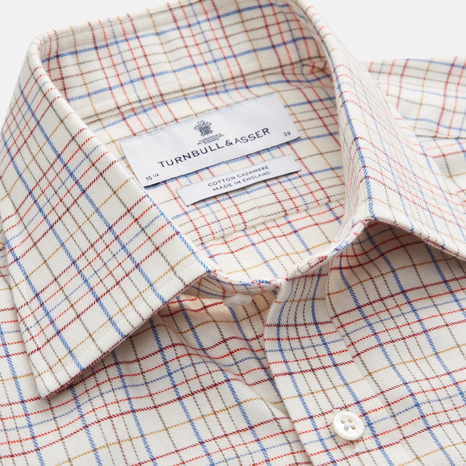 View 2 of product The Turnbull & Asser Red Multi Check Regular Fit Cotton-Cashmere Shirt features a T&A collar, 3 button cuffs, and a multicolored check pattern on white, shown laid flat against a white surface.
