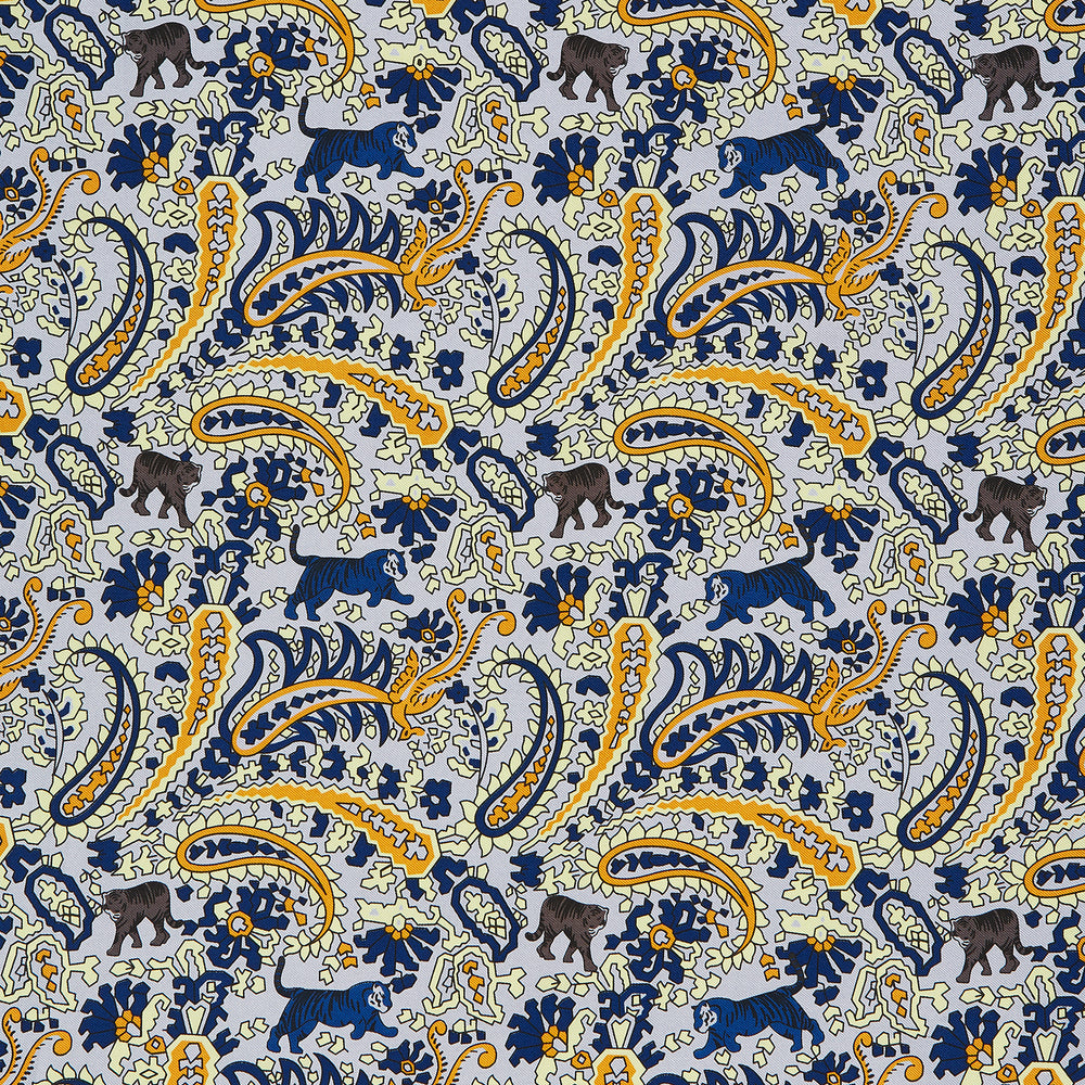 The Blue and Yellow Paisley Tiger Silk Pocket Square by Turnbull & Asser features a light blue base with paisley, elephants, tigers, and floral motifs—highlighted by a blue border. An elegant choice to pair with any Turnbull shirt.